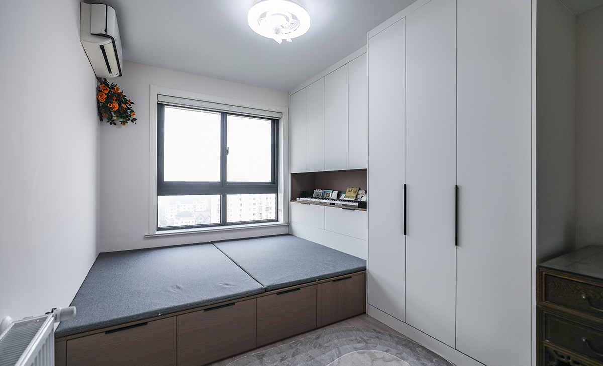 小次臥做了榻榻米和寫字臺，平時做書房用，榻榻米供外孫住，造型上以方正為主，色彩上以淺色為主，榻榻米下面和衣柜解決主人的收納，1.5米長的寫字臺可以解決主人的辦公需求。