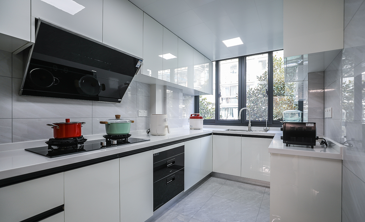 該套房子廚房空間較大，U型三面櫥柜，采用高光pet門板，顏色簡潔明快，材質干凈和好打理，白色的吊頂和白色的上、下櫥柜相呼應，石英石臺面干凈、好打理，各種廚房電器全部配齊，滿足主人制作各種美食的需求。