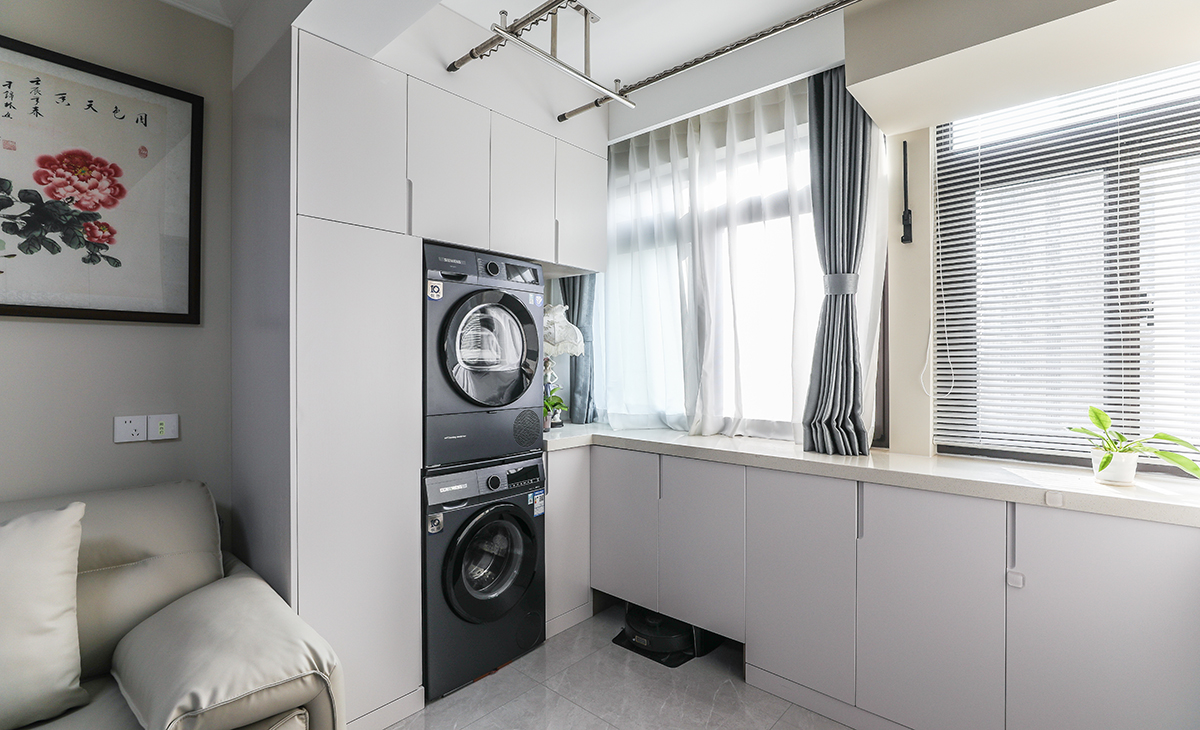 陽臺(tái)與客廳打通增大空間的同時(shí)也做了大量的儲(chǔ)物，洗衣機(jī)烘干機(jī)上下疊放，邊上做了一組家政柜放置吸塵器等家政用品，小小的空間有大大的利用。