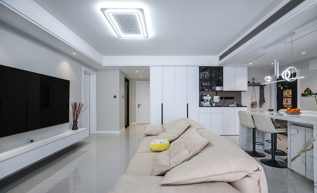 客廳側(cè)面還安排了一排綜合了鞋柜、餐邊柜、展示柜、收納柜為一體的滿墻收納柜，既不影響整體空間，也可以有效的把客餐廳所需的東西收納起來。