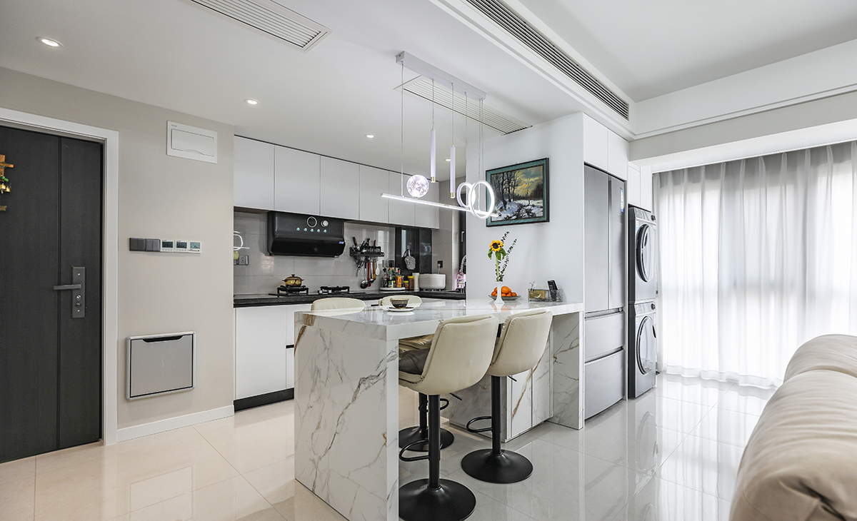 廚房與客廳之間用高吧臺及電器柜隔開，既解決了冰箱、洗衣機、烘干機和熱水器的安置問題，也不影響整個空間的延伸感、通透感。