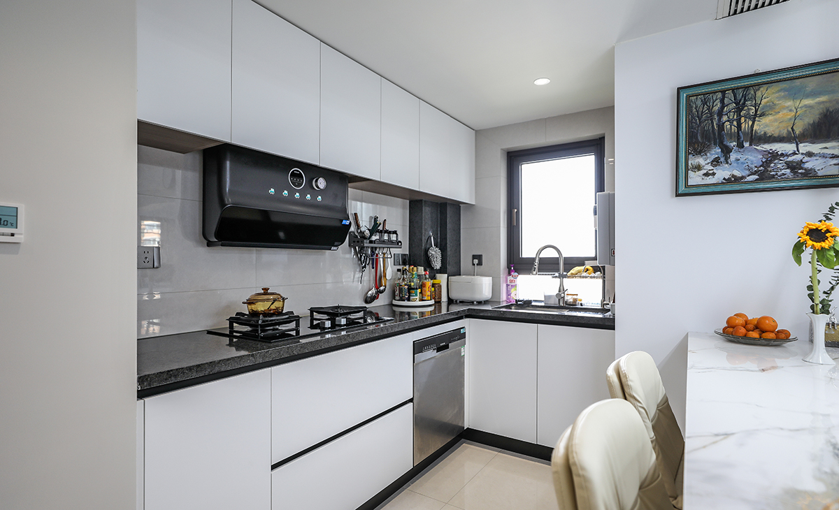 敞開式廚房，L型櫥柜，洗、切、炒動線合理，白色的柜體、深灰的臺面和黑色的五金，顏色簡潔明快，材質(zhì)干凈好打理。還安排了一個洗碗機解決了家里主人誰洗碗的煩惱。