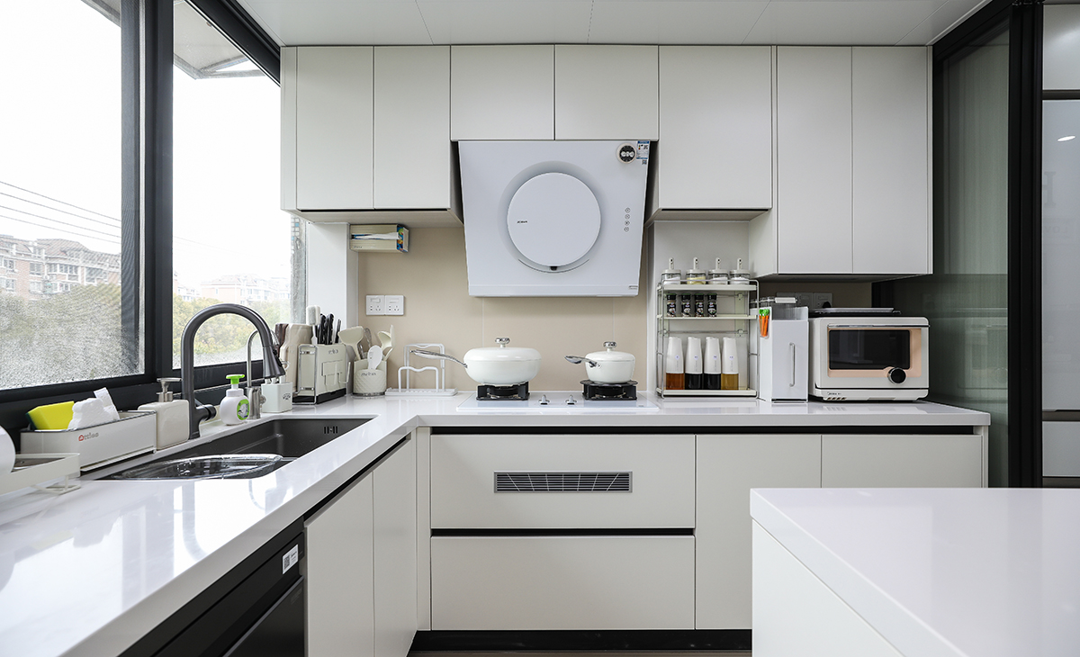 該套房子廚房空間很大，U型三面櫥柜，顏色簡潔明快，材質要干凈和好打理，白色的吊頂和米色的上櫥柜、下櫥柜相呼應，石英石臺面干凈、好打理，各種廚房電器全部配齊，滿足主人制作各種美食的需求