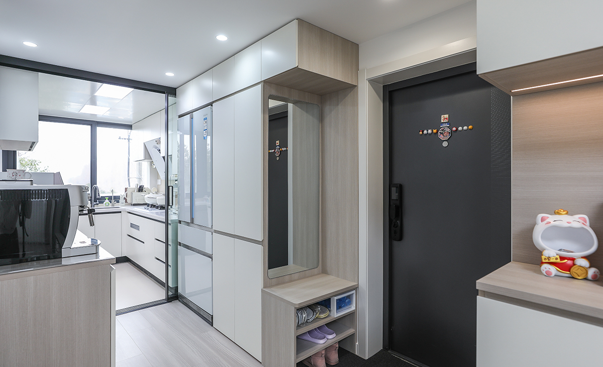 進戶鞋柜設計采用下方換鞋凳、中間鏡子，讓進門空間變寬敞、明亮。側面是衣帽柜，讓鞋柜功能齊全，顏色和防盜門、進戶門套能夠協調。