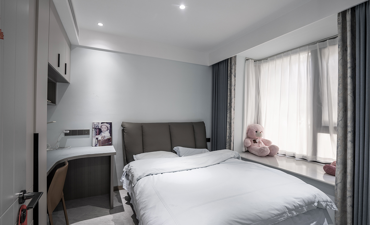 兒子房間有一個大飄窗，讓空間有延伸感，衣柜和書桌連成一體，既能掛衣服又能放學(xué)習(xí)用品，頂面采用無主燈設(shè)計，空間敞亮不壓抑。
