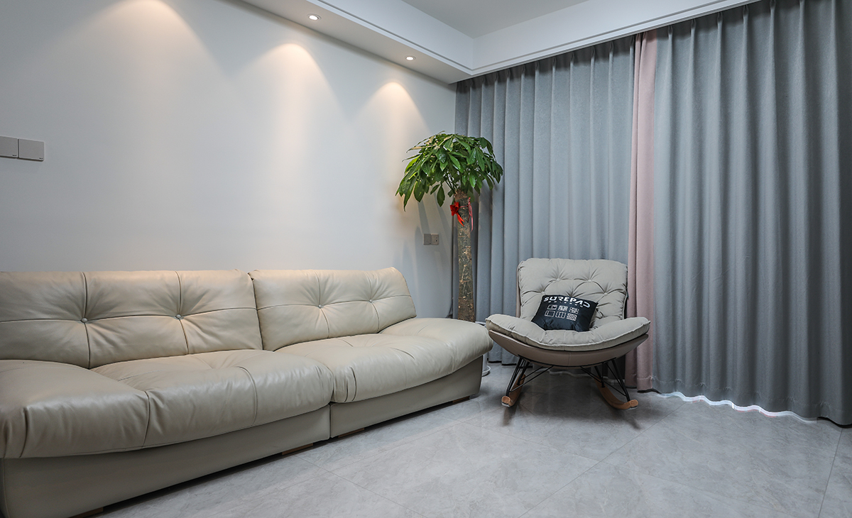 沙發背景刷米白色涂料，搭配白色的沙簾和高級灰的窗簾，沙發背景留白設計，色調上墻面涂料和沙發用淺色，窗簾用深色，深淺搭配的錯落有致，既溫馨又簡潔。
