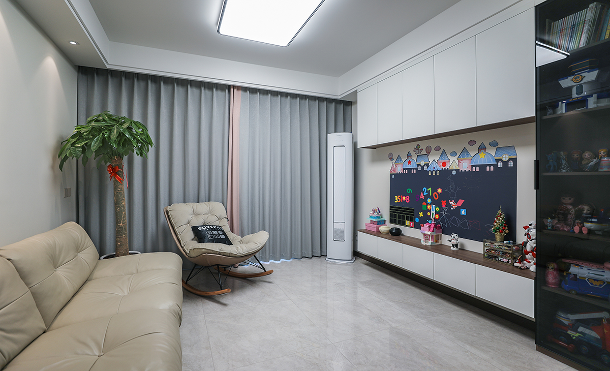  客廳開間很大，沙發上空的射燈提升了空間整體的氛圍感，米黃色皮質沙發立刻檔次提高很多，旁邊放一組單人沙發，客廳空間也很寬闊。吊頂造型上采用雙眼皮吊頂。地面采用淺灰色地磚。造型和色調上無不給人以簡潔、大氣、時尚的感覺。