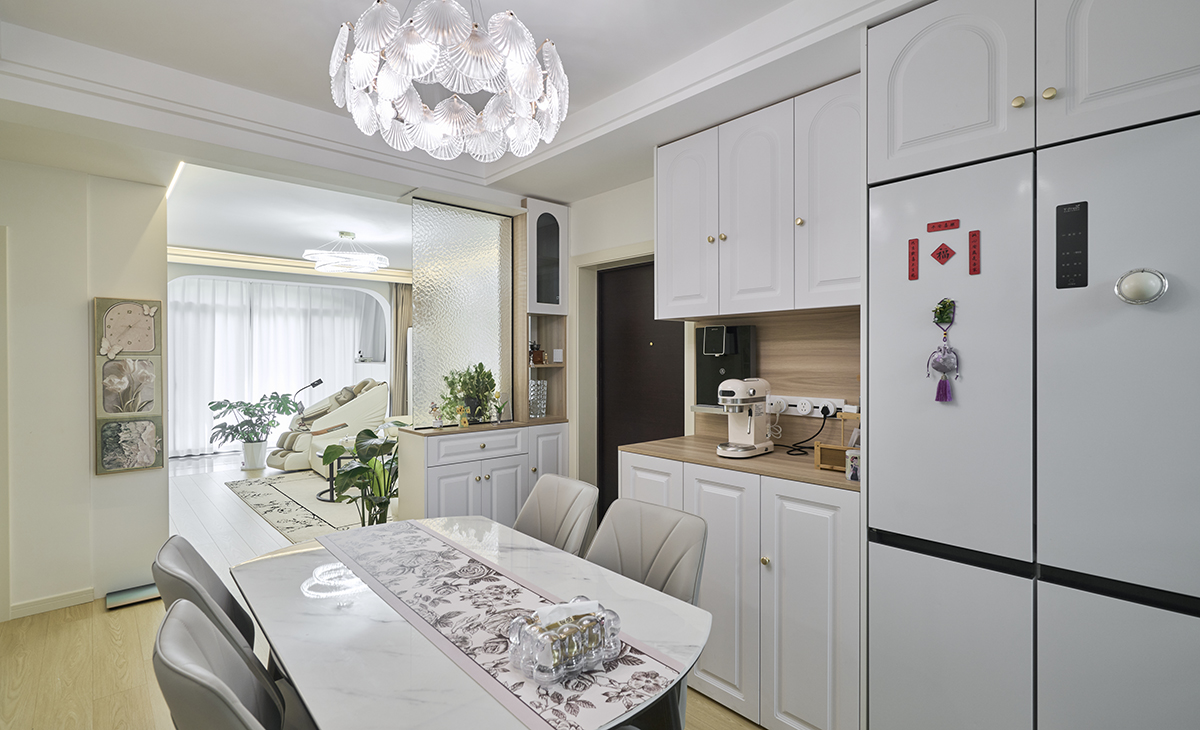 餐廳空間比較方正，冰箱和餐邊柜連成一體，中間有管線機、頂面花瓣型吊燈是一大亮點，雙眼皮圍邊的造型，玄關處的花瓶把空間點綴地恰到好處。