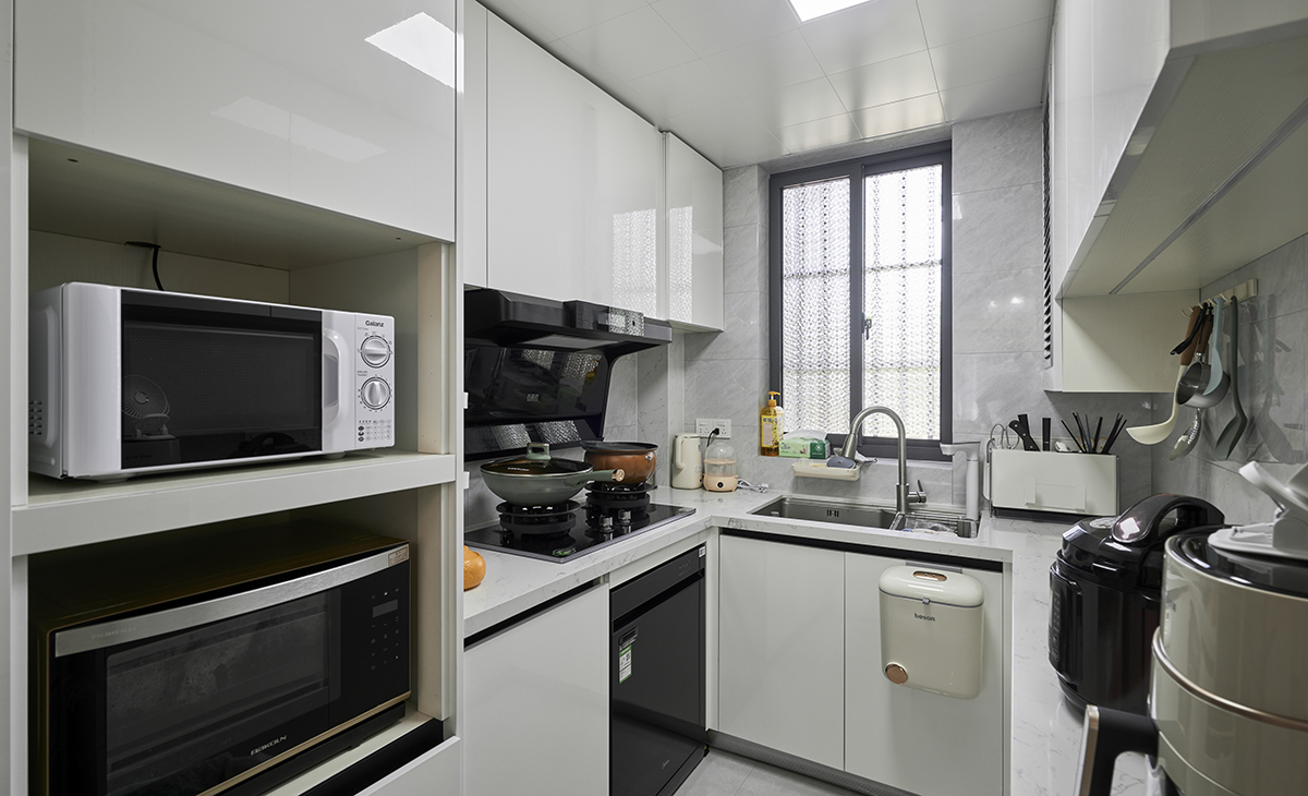該套房子廚房空間很大，做成U字型櫥柜，蒸烤一體機放煤氣灶立柜中，煤氣灶下方配洗碗機，上柜下柜都是米白色，臺面白色，方便打理，墻地磚的顏色和櫥柜顏色搭配地很自然，客戶不斷地夸贊設計師對色彩的精準把握。