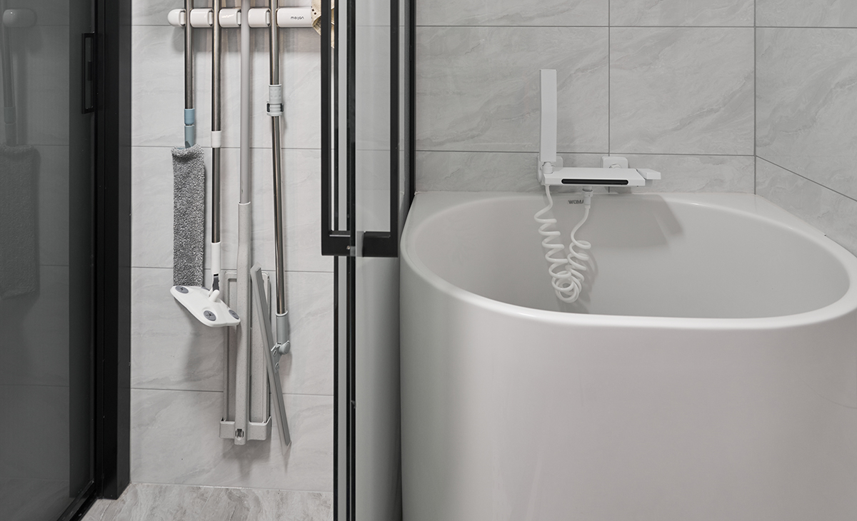 衛生間濕區不僅有淋浴房可以沖淋，還有一個小浴缸，方便主人泡澡，槍灰色邊框淋浴房和墻磚的顏色，明暗錯落有致。