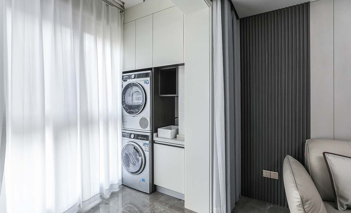 陽(yáng)臺(tái)是晾曬衣物的場(chǎng)所，一側(cè)洗衣機(jī)和水池，一側(cè)為儲(chǔ)物柜，顏色以白色為主，儲(chǔ)物柜白色門(mén)板和門(mén)套相搭配，超大玻璃窗讓陽(yáng)光柔和的照進(jìn)來(lái)，很舒適、很愜意。