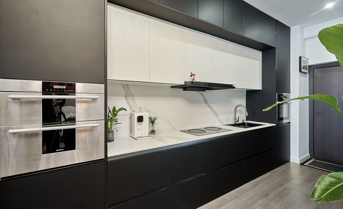 該套房子廚房空間很大，做成一字型櫥柜，蒸烤一體機，上柜下柜都是深灰色，白色的吊柜和巖板臺面，搭配的很大氣，客戶不斷地夸贊設計師對色彩的精準把握。