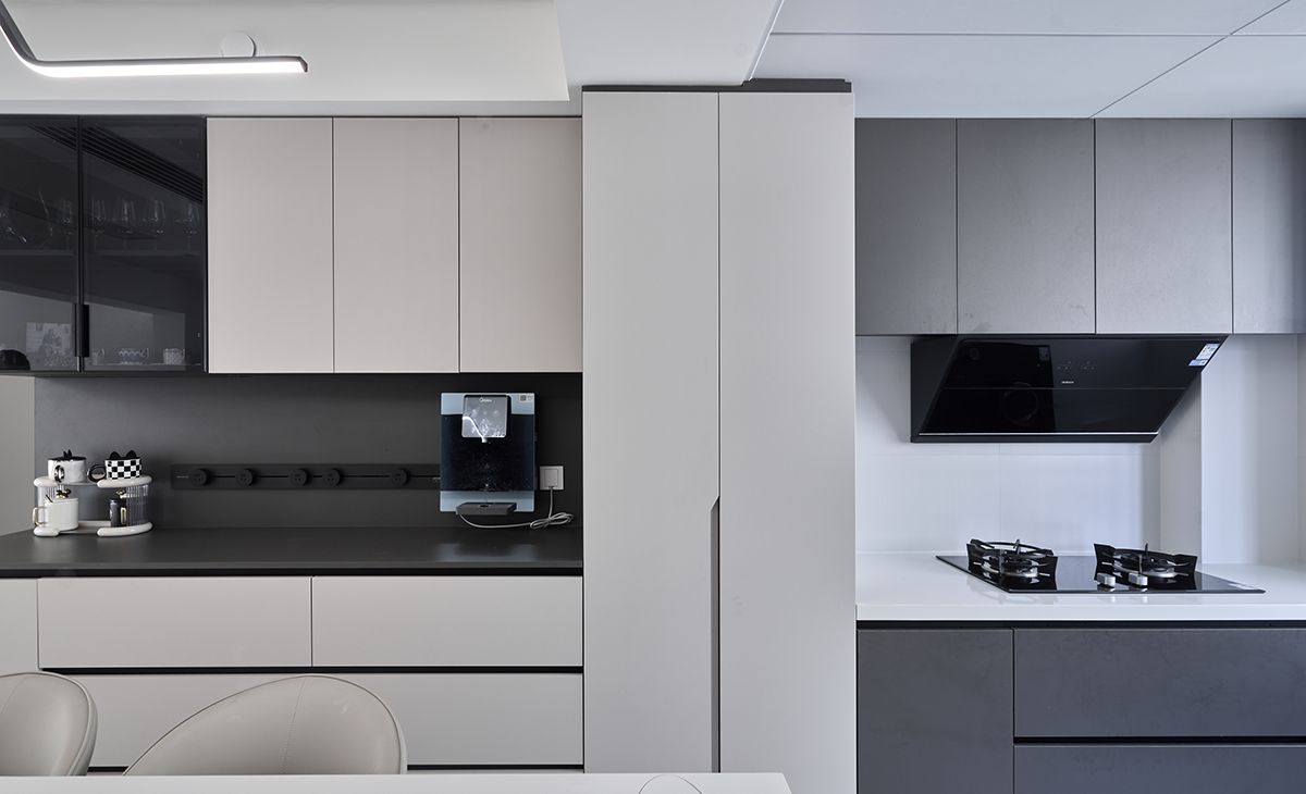 該套房子廚房空間很大，做成U字型櫥柜，蒸烤一體機放立柜中，煤氣灶下方配雙層碗籃、調味籃，上柜下柜是深灰色，臺面白色，方便打理，墻地磚的顏色和櫥柜顏色搭配地很自然，客戶不斷地夸贊設計師對色彩的精準把握。