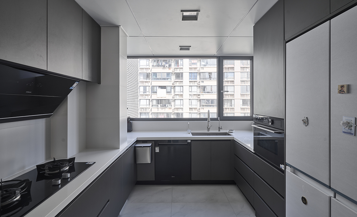 廚房U型廚柜，開放式，水池邊上是14套洗碗機，中央軟水和凈水都在水池下方，淺灰色雙門冰箱，讓廚房空間顏色明暗有序，從深到淺，色調很豐富。