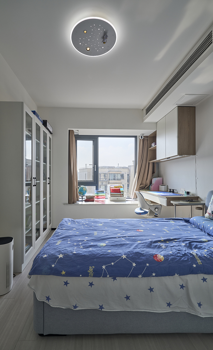 兒子房也有大飄窗，利用飄窗做一個懸挑寫字臺，上面吊柜，寫字臺對面又有一排書柜，有效收納了兒子的書籍。