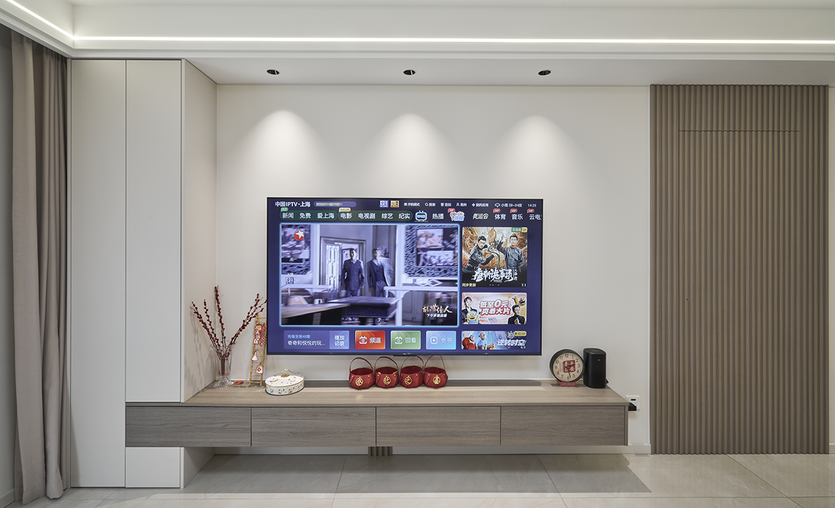 電視背景刷米色涂料，灰色的沙簾，電視背景柜和米色背景墻渾然一體，色調搭配一致，既溫馨又簡潔。