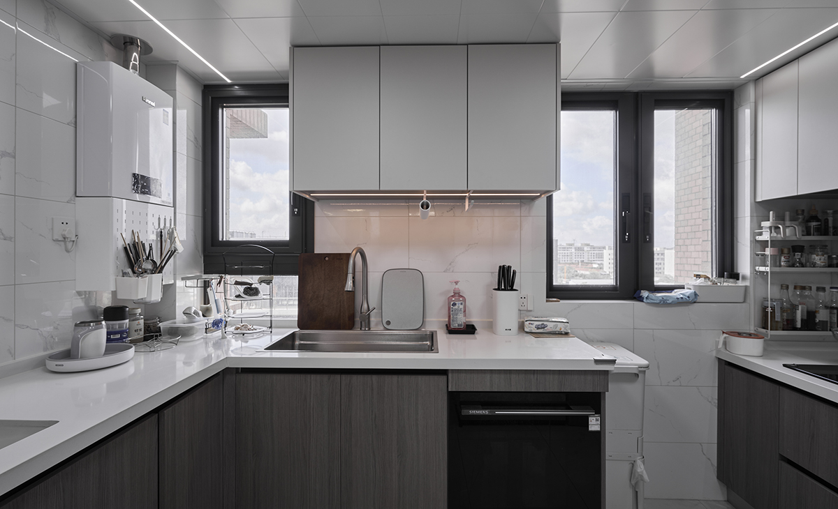 廚房空間很大，U型兩面櫥柜，顏色簡潔明快，材質要干凈和好打理，白色的吊頂和高光的的灰色櫥柜相呼應，石英石臺面干凈清爽，各種廚房電器全部配齊，滿足主人制作各種美食的需求。