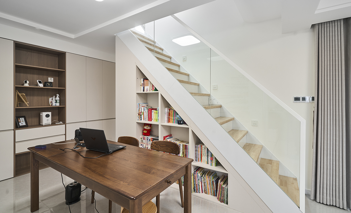 樓梯下方的三角區域空間很大，放很多書籍，此處作為主人的辦公區域，側面展示柜，展示主人的工藝品及所獲獎勵。