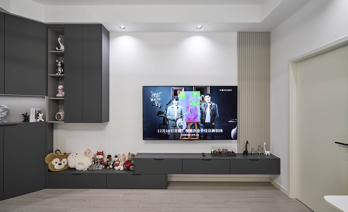 電視背景墻區域，整體灰色的電視柜從玄關衍生過來，相互響應，奶咖色的木格柵起到了畫龍點睛的作用，干凈的背景墻配上70寸電視，一直呆在客廳也愿意啊