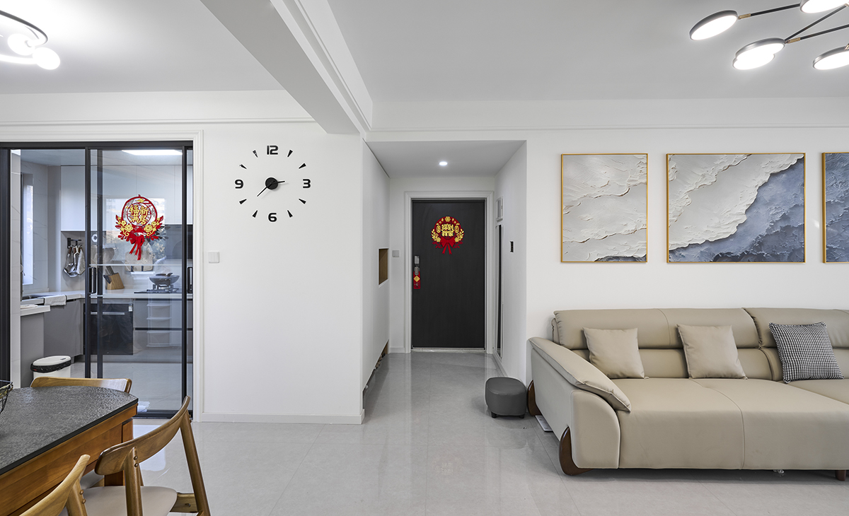 玄關柜設計，柜子中間有一個開放的展示區，內部為淺木色。展示區內擺放了一些裝飾品，包括紅色的花卉裝飾、一個小玩偶、一個編織籃子和其他一些小物件，這些裝飾品為空間增添了溫馨的氛圍。柜子下方暗藏燈帶，方便進出換鞋。這種柜子設計既美觀又實用，既能展示主人的品味，又能提供儲物功能。對面安裝裝飾鏡