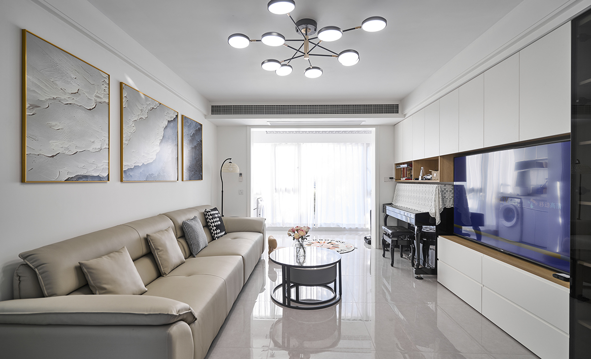 客廳是接待客人的空間、是家庭裝修的亮點所在、也是一家人活動頻率最高的區域，米色皮質沙發，體現高端華麗，吊頂造型上采用雙眼皮吊頂，地面采用淺灰色地磚，沙發背景采用裝飾掛畫。造型和色調上無不給人干凈、整潔、溫馨的氣息。