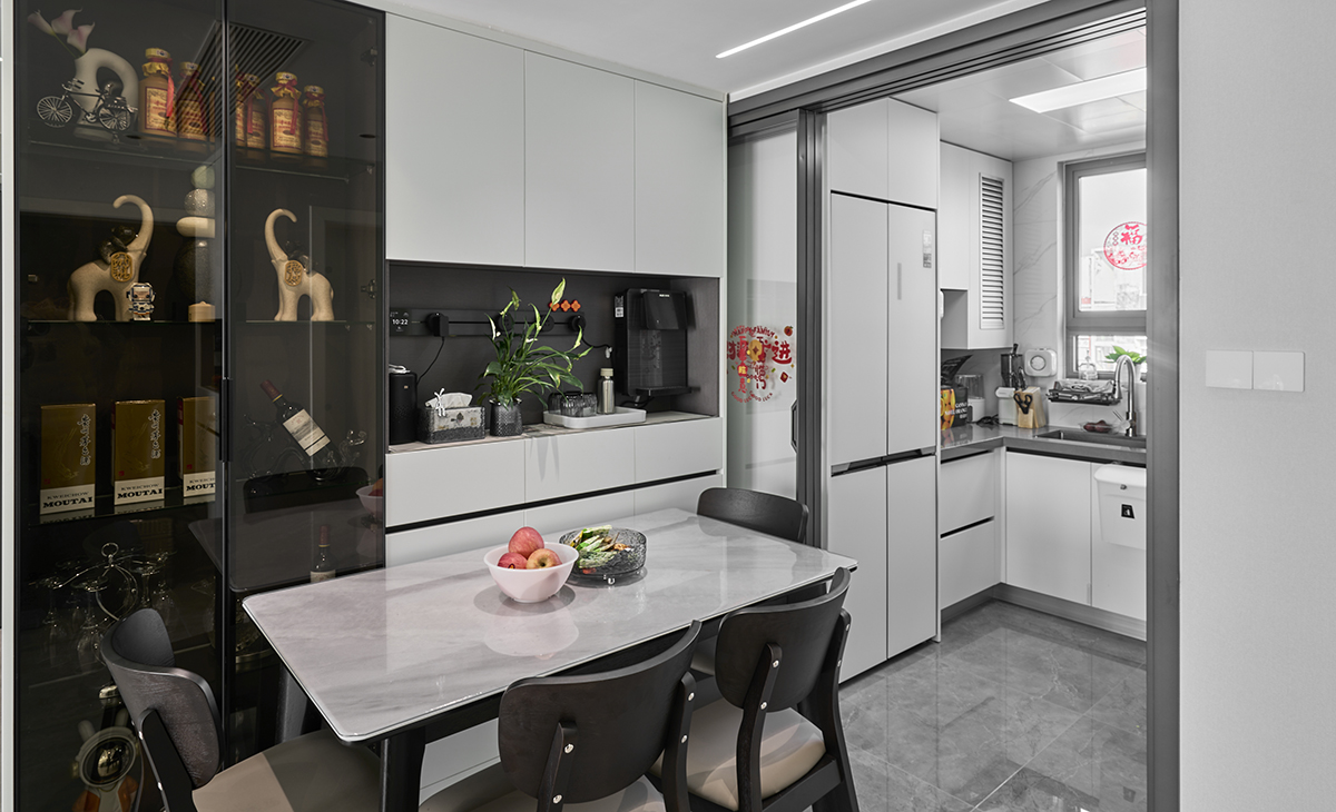 餐廳白色的櫥柜巧妙融入墻壁，白色島臺與純黑餐桌形成對比，沉穩而不失格調。餐廳、廚房與客廳無縫銜接，營造出溫馨的生活氛圍?。