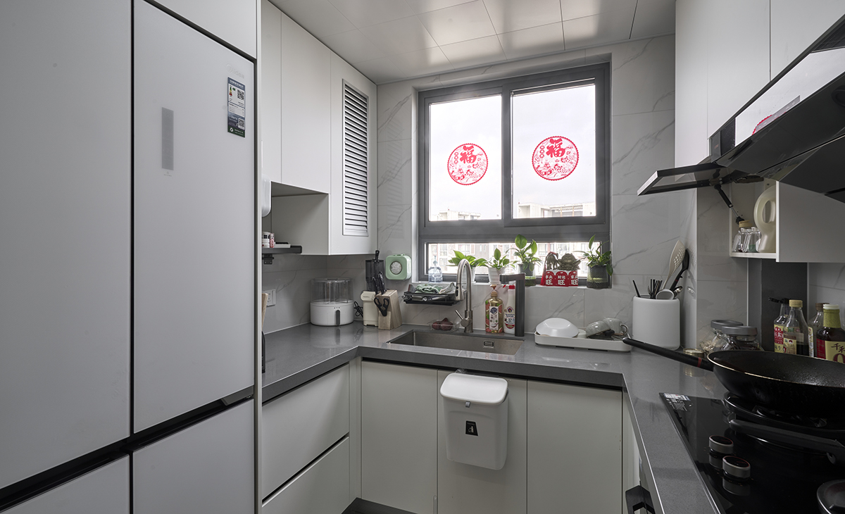  靠窗設計保證充足光亮；右邊黑色主打的廚房區域，櫥柜和油煙機選用深沉黑色。