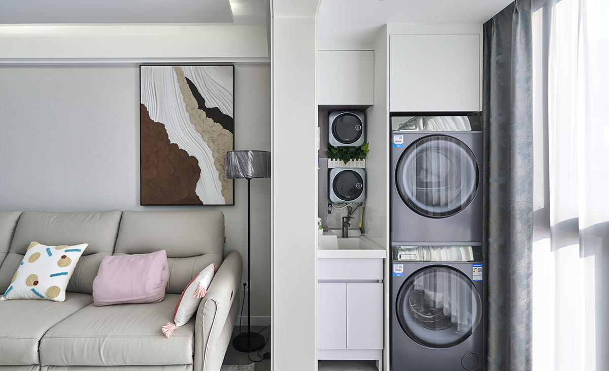 該套房子陽臺的空間利用的很完美，定制洗衣機柜，儲物空間很大，有一個小水池也能洗洗小東西，上面做一個吊柜，使用起來很方便，把空間襯托的完美無霞。