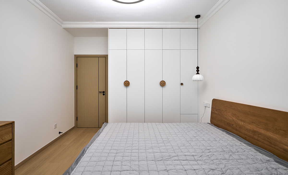 主臥采用白色衣柜+原木色實木床和地板，灰色床單，顏色由深到淺，錯落別致，床頭小吊燈作為氛圍燈，和主燈一起把空間照亮，把木色北歐風格詮釋的淋漓盡致。