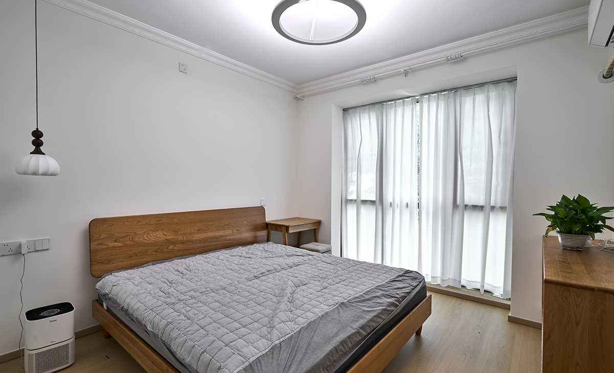 主臥落地窗配白色紗簾，原木色梳妝臺，五斗柜，上方一盆綠植，把空間點綴的生動活潑、綠色有生機，主臥頂面吸頂燈是一大亮點，把空間點綴地恰到好處。