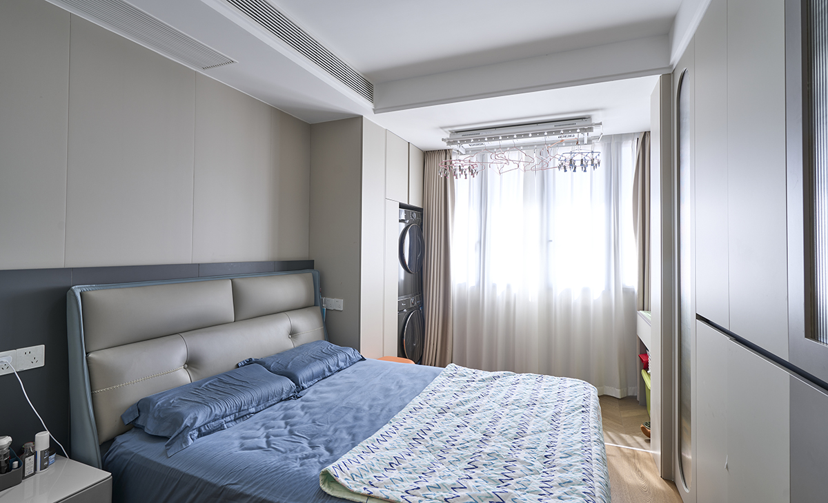 主臥皮質造型床和天空藍色床品和地板的顏色相呼應，衣柜和顏色也是現代風格的分段式內嵌拉手，頂面中央空調吊頂和雙眼皮結合也不呆板，比較靈活。窗簾也是一個亮點，米色的布簾搭配白色的沙簾讓整個空間明亮和增大很多。