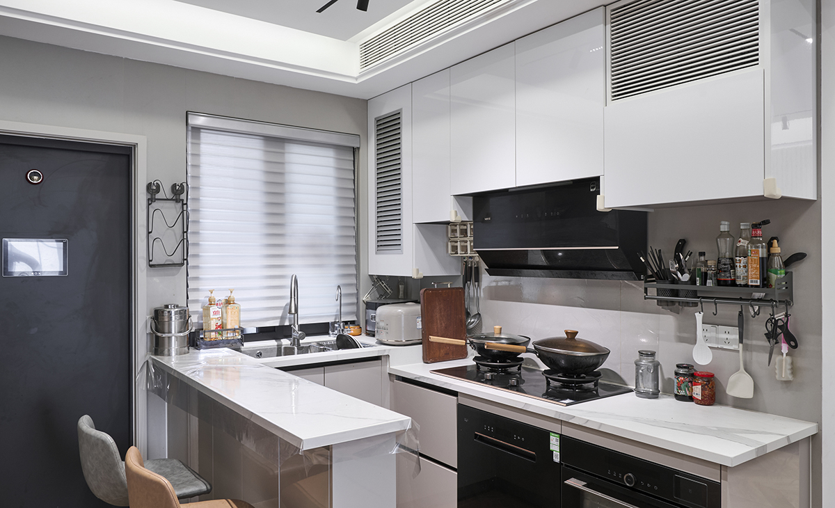 該套房子廚房是開放式，做成U字型櫥柜，煤氣灶下方配洗碗機和蒸烤箱，上柜下柜分色處理更顯層次感，臺面巖板，方便打理，墻地磚的顏色和櫥柜顏色搭配地很自然，客戶不斷地夸贊設計師對色彩的精準把握。