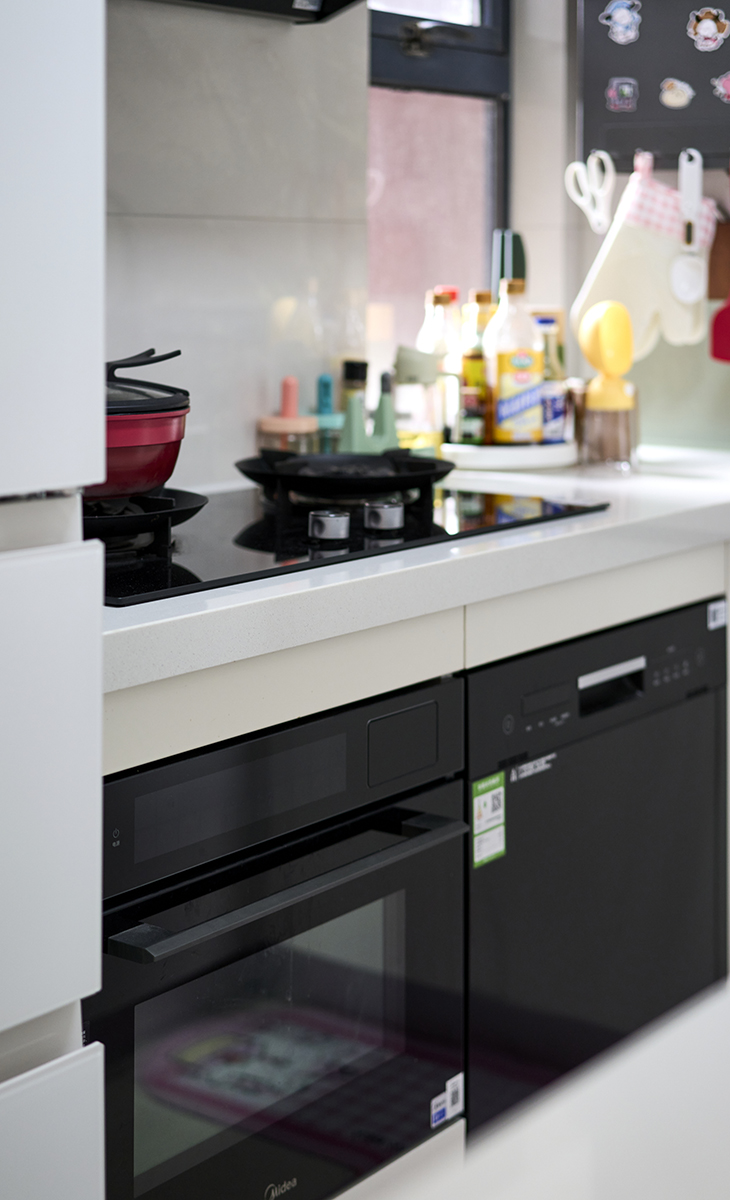 該套房子廚房是開(kāi)放式，做成U字型櫥柜，煤氣灶下方配洗碗機(jī)和蒸烤箱，上柜下柜儲(chǔ)物空間滿(mǎn)滿(mǎn)當(dāng)當(dāng)，臺(tái)面巖板，方便打理，墻地磚的顏色和櫥柜顏色搭配地很自然，客戶(hù)不斷地夸贊設(shè)計(jì)師對(duì)色彩的精準(zhǔn)把握。