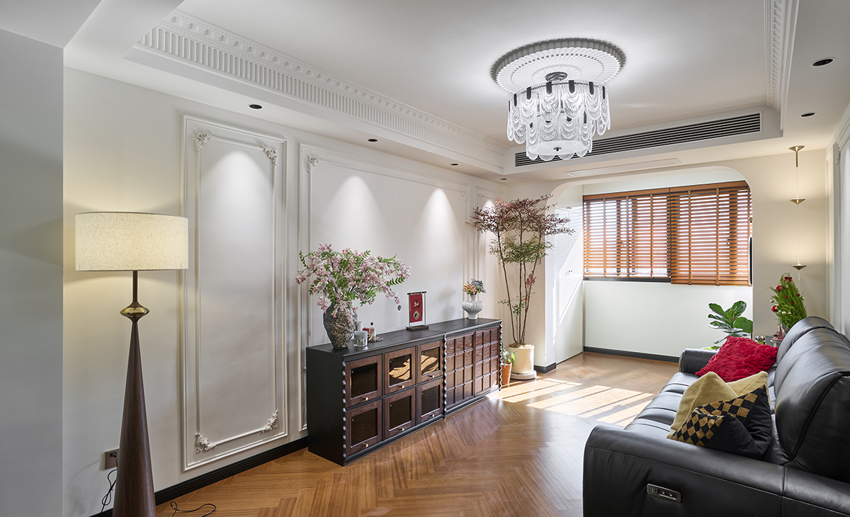 客廳是接待客人的空間、是家庭裝修的亮點所在、也是一家人活動頻率最高的區域，黑色皮質沙發，人字拼木紋復古地板，吊頂造型上采用回字頂+成品石膏虎頭線+鋼琴線，古木色的電視柜，陽臺拱形門洞。自然光透過落地窗灑落，與暖色燈光交織，營造溫馨社交氛圍