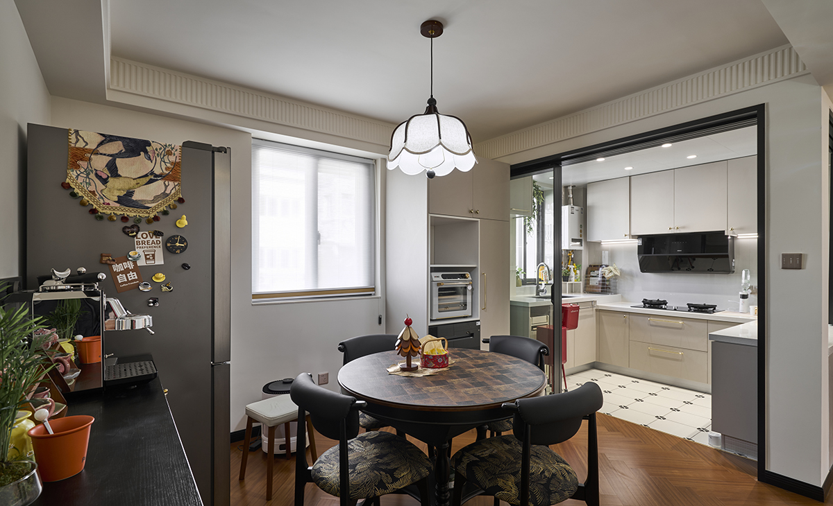 餐廳空間比較方正，集合了很多的電器，大大的解放雙手，臺面餐桌搭配皮質餐椅，開放式置物架與餐邊柜滿足收納與展示的雙重需求。傍晚時分，燭光與吊燈交相輝映，一杯紅酒、一曲爵士，生活的詩意在舉杯間悄然流淌，讓日常也成為儀式的注腳。