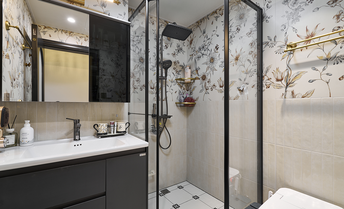 衛生間墻面鋪滿帶植物枝葉圖案的壁紙，復古基調搭配小清新色調，地面小花磚多樣化鋪貼，形成對比鮮明卻不沖突的視覺效果。  