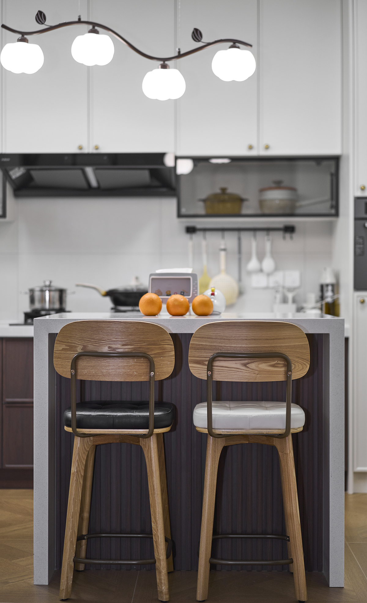 黑白椅挨著煙火氣  這方寸小臺，是中古調里的早餐與閑，吧臺沿的淺白，碰著木椅的暖棕；隨手放的橘子，是復古廚房最鮮活的小點綴