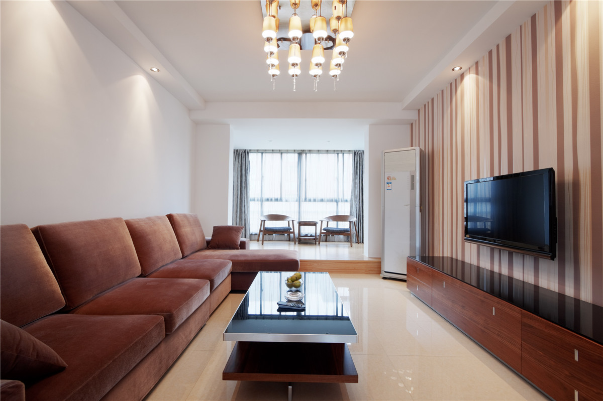 客廳中條紋圖案的壁紙在白色的環境中塑造出有型的立面效果。 整個空間中只有少許的裝飾品，干凈，整潔的，落落大方。色澤統一的紅色家具莊重嚴謹的感覺中又有一份活躍，加上多盞筒燈的點綴，空間很溫暖，為方便舒適的生活做出了完美的詮釋。
