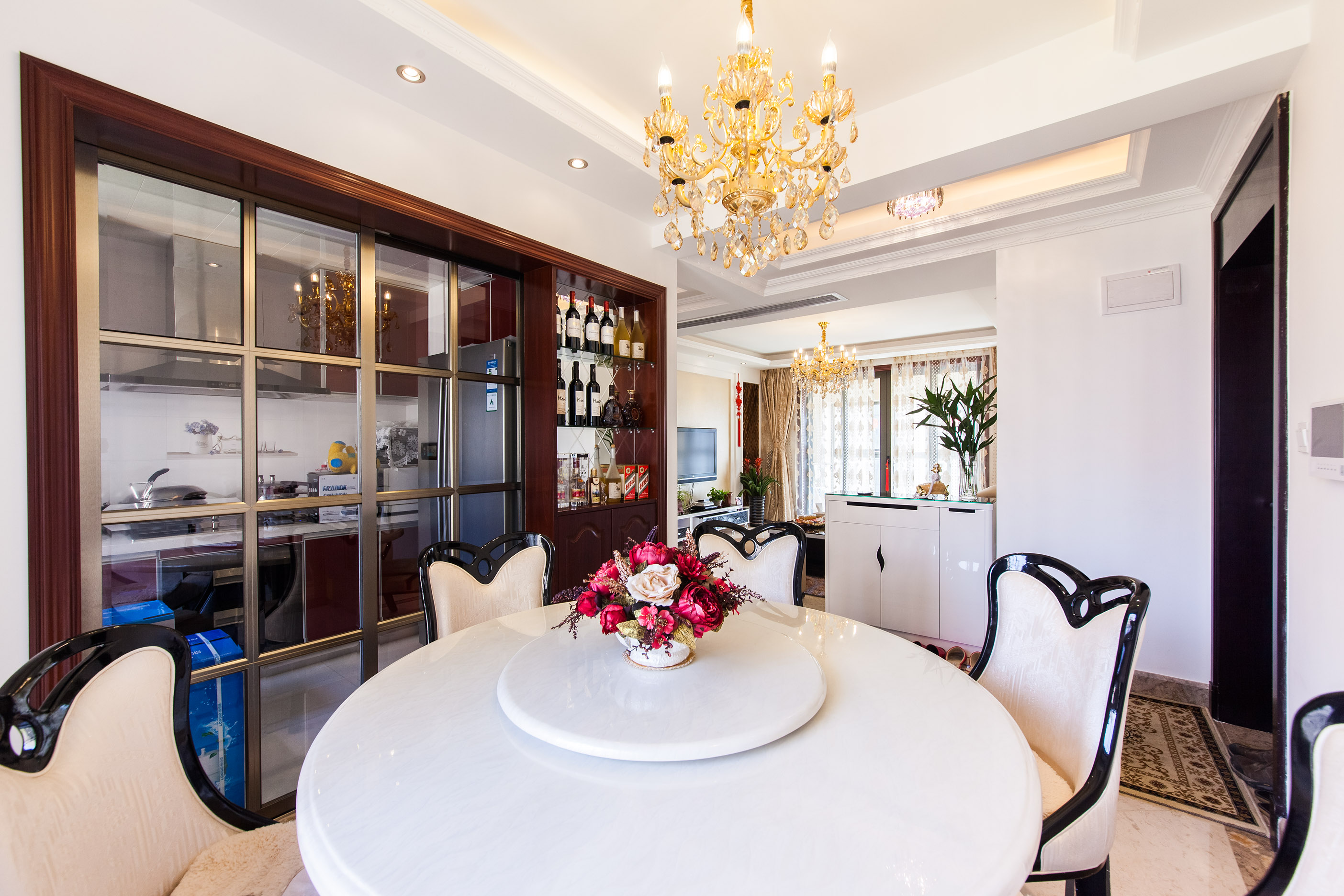 餐廳白色的餐桌，配上黑色邊框的餐椅，整體色調是那么的協調，紅木色的裝飾酒柜，顯現出業主的高尚品味，漂亮的水晶燈使得高貴的空間更加的濃烈。
