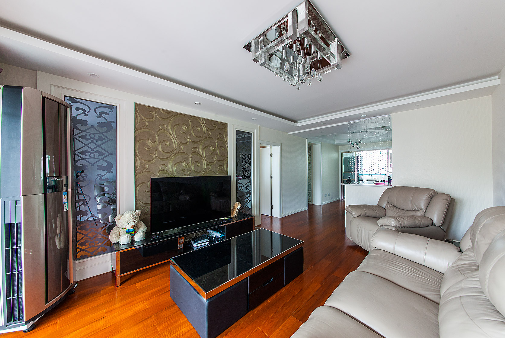 客廳最大的亮點，無疑是背景墻，金色墻紙沖淡了灰鏡與白色烤漆這個萬能組合，所衍生出的冷峻氣息，使得客廳永遠不令人感到單調枯燥。
