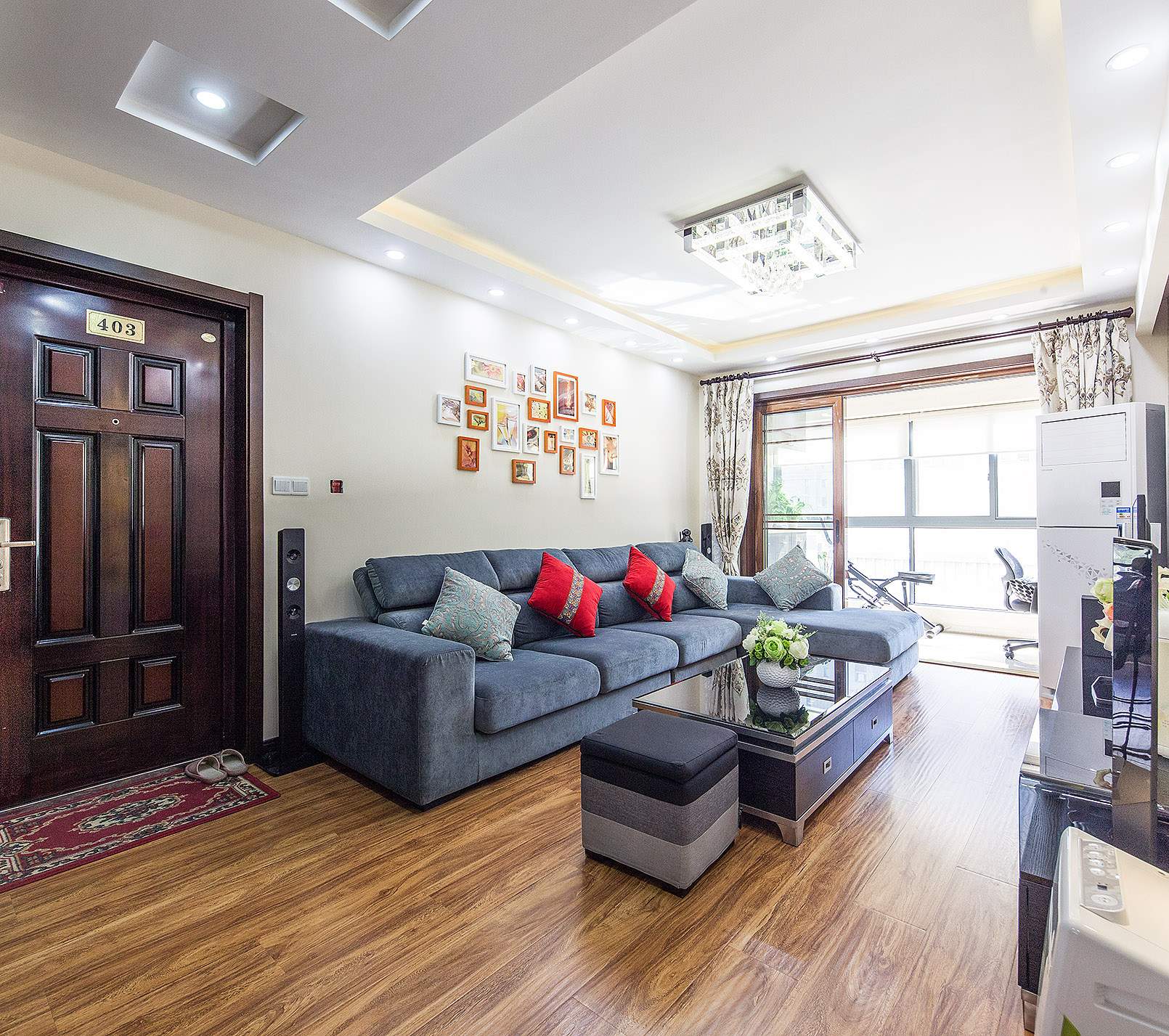 不規則的裝飾畫在燈光的照射下使沙發背景頓時活躍起來，紅色的抱枕使厚重的沙發顯得輕巧，布藝窗簾，雅致的水晶燈，營造合諧的氛圍。
