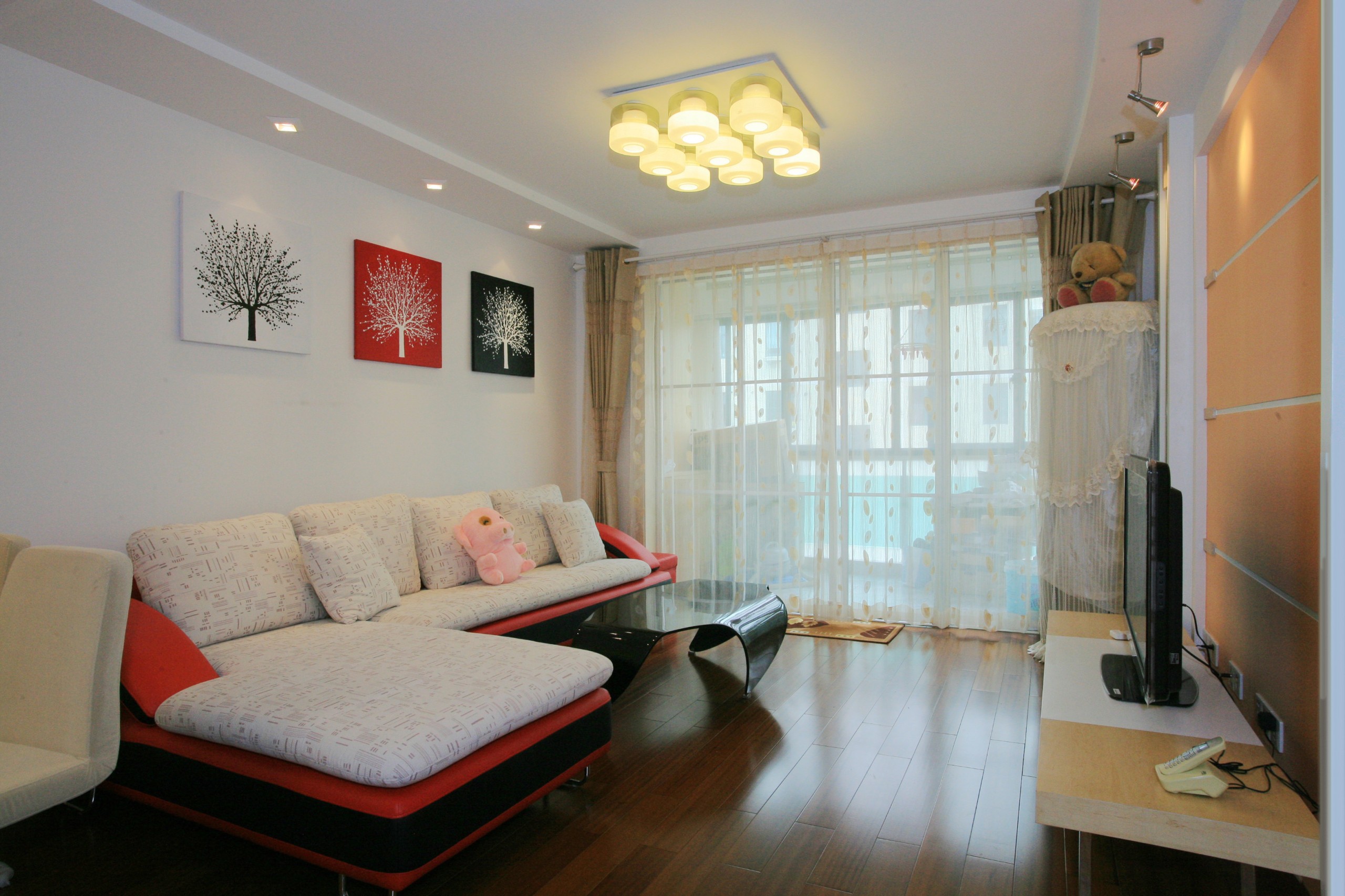 一縷縷陽光透過白色蕾絲般的窗簾散在幽香的地板上，碎花紋飾的紗發給居室增添了靈動自然的韻味，各種燈飾的光同光滑的地板輝映出更加靈動的韻律。墻上的掛畫雖然簡單，但它開放的枝蔓展現出一種勃發的生命力。
