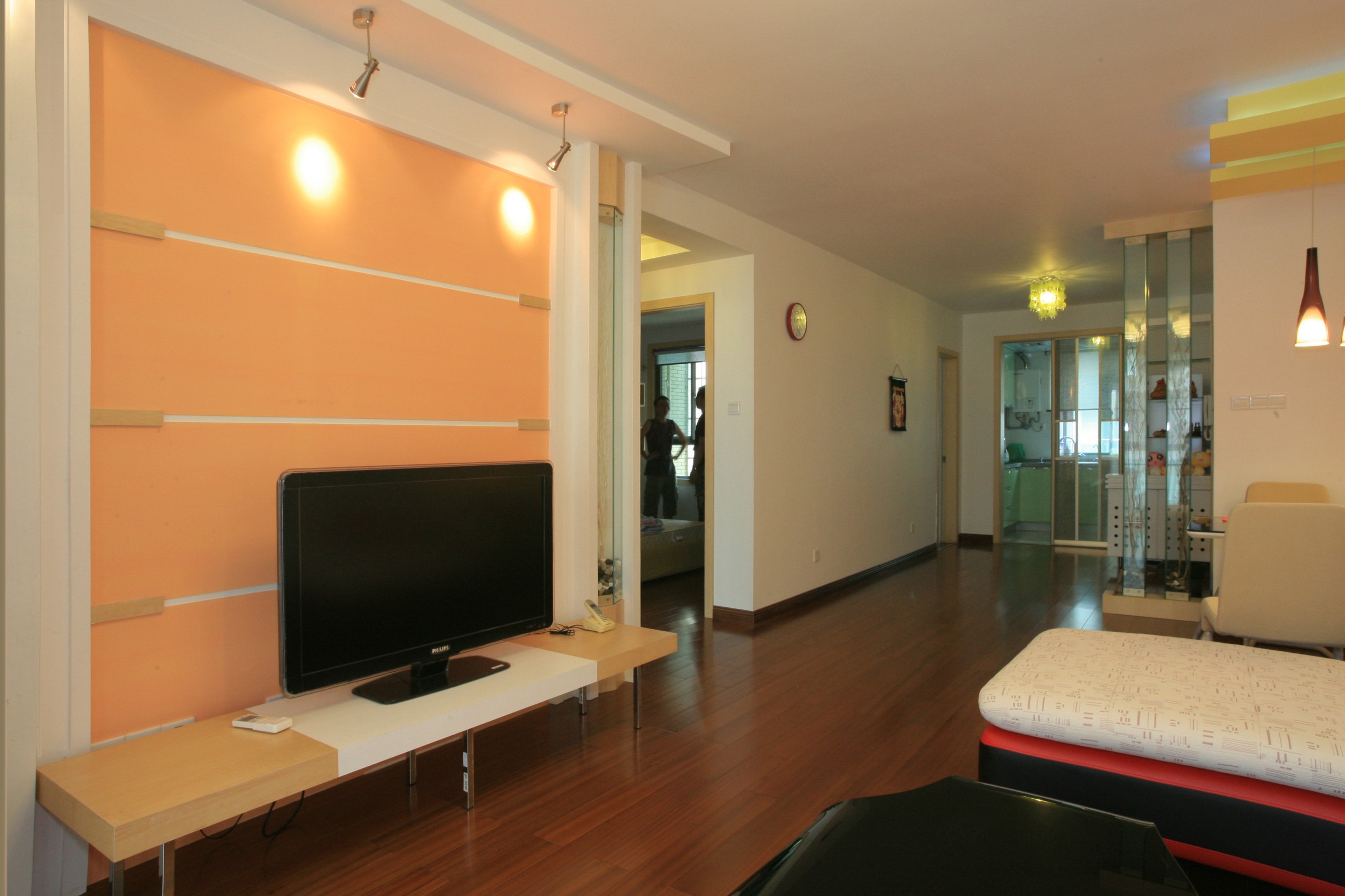 橙色的電視背景墻彰顯了生命的活力，在淡黃色的燈光下更顯妖嬈，幽香的實木地板將房間內的空間有機的連接到一起。踩在這樣的地面之上，既能找到一份舒適，又有一種與大自然親密接觸的和諧感。