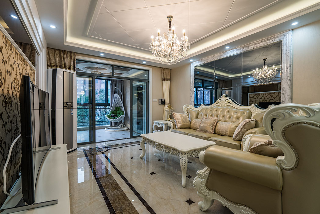 客廳古典沙發(fā)坐陣，拼花的防大理石地磚，把它襯托的更加華麗，也彰顯主人的高貴身份。電視背景墻茶鏡與墻紙的完美結(jié)合，既時(shí)尚有突出了重點(diǎn)。
