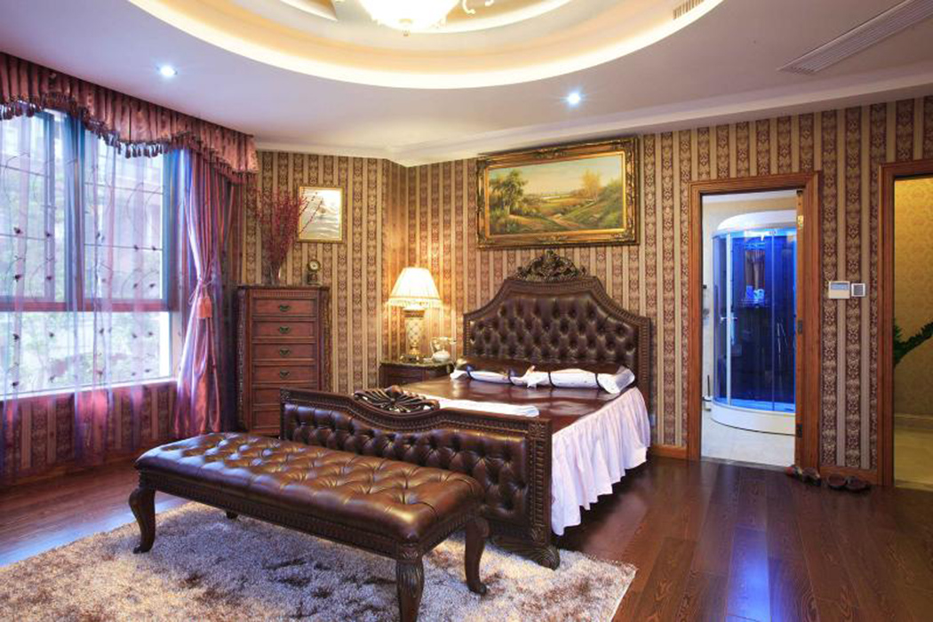 臥室用經過打磨處理之后的地板透著一股滄桑美，那是一種讓人安心的依靠感。家具造型和壁紙花紋在延續新古典元素的同時作了簡化，營造出發一個溫馨舒適的休憩空間。
