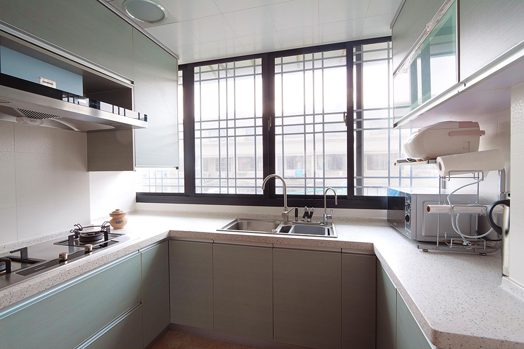 廚房間的搭配可算是別有用心，水槽處的柜面使用的是淺色的木色，呼應客廳處的木色，其余的柜體使用淺淺的綠色，使人心情愉快。
