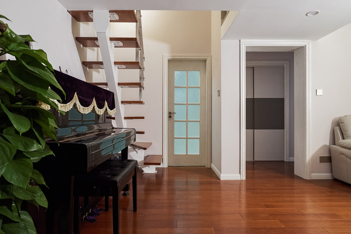 客廳為了配合業(yè)主家的米白色沙發(fā)，地面采用了環(huán)保的實木地板，家具采用黑白系列，簡單干凈。沒有過多的裝飾，頂面沒有做過多的修飾主要考慮到業(yè)主的房型是loft，需要搭建，吊頂?shù)脑挄旱蛯痈咭矔谷瞬皇娣皂斆娌蛔鲞^多裝飾。電視背景墻采用灰色的地板上墻，給人以穩(wěn)重的感覺，客廳樓梯采用的是經(jīng)濟實用的鋼木樓梯，同時讓整個客廳顯得不那么單調(diào)。
