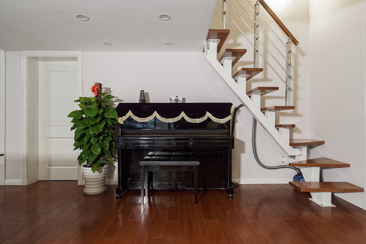 客廳為了配合業(yè)主家的米白色沙發(fā)，地面采用了環(huán)保的實木地板，家具采用黑白系列，簡單干凈。沒有過多的裝飾，頂面沒有做過多的修飾主要考慮到業(yè)主的房型是loft，需要搭建，吊頂?shù)脑挄旱蛯痈咭矔谷瞬皇娣皂斆娌蛔鲞^多裝飾。電視背景墻采用灰色的地板上墻，給人以穩(wěn)重的感覺，客廳樓梯采用的是經(jīng)濟實用的鋼木樓梯，同時讓整個客廳顯得不那么單調(diào)。
