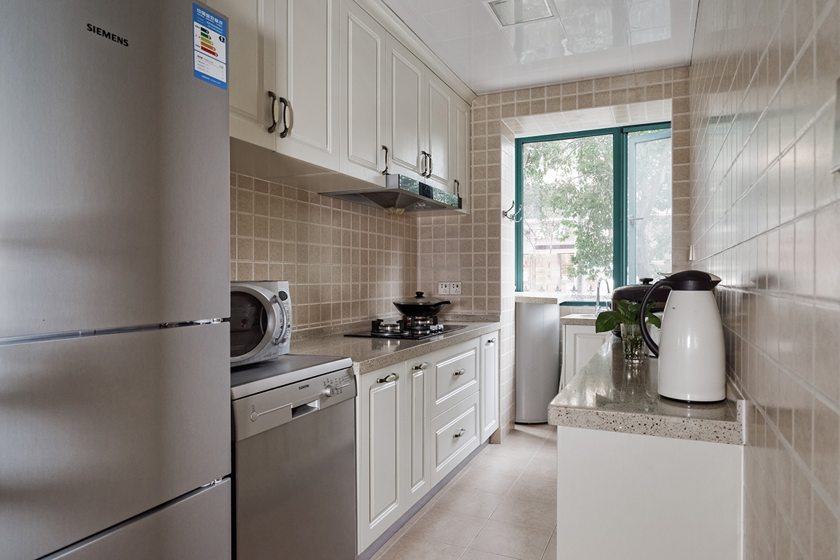 廚房空間不是很大，還是狹長型戶型，借先天的這種結(jié)構(gòu)兩邊做了吧臺，左邊吧臺用來燒菜右邊有來房洗好的菜或者已經(jīng)做好的菜，比較方便，洗菜池放在了陽臺，能夠更好地利用空間。色彩上采用米白色的模壓板，加上米黃色的墻面磚，使得空間得以延伸，看上去顯得更寬敞