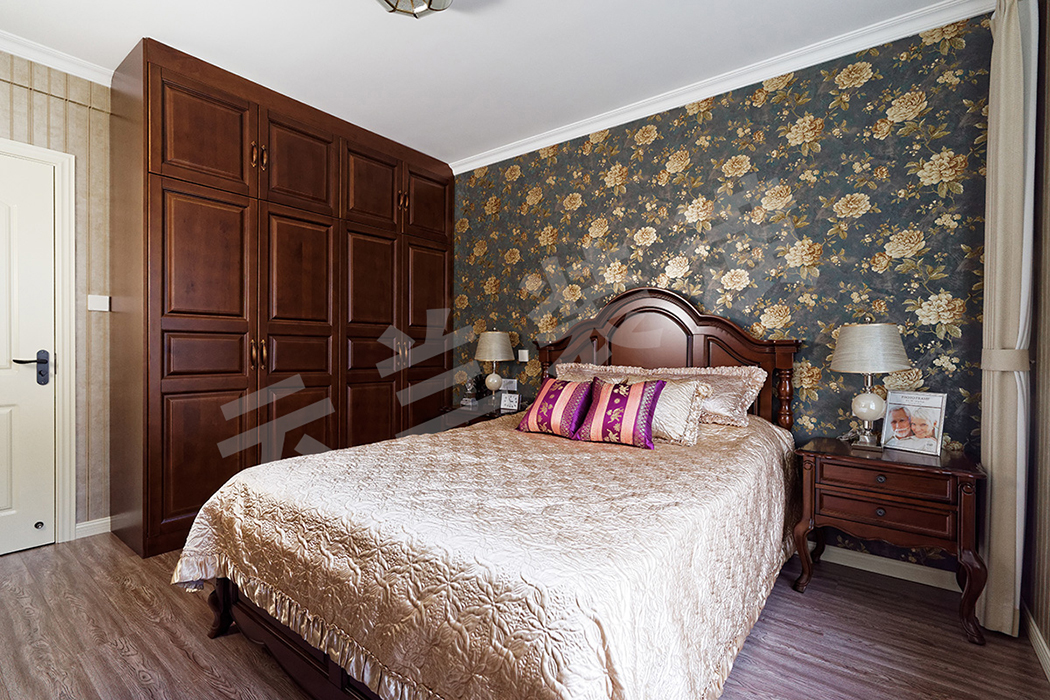 主臥整體使用柔和的條紋壁紙，而床頭背景墻采用了大花壁紙，避免了深色家具的壓抑感，使這一對中年夫婦的臥室溫馨而又不失穩(wěn)重。
